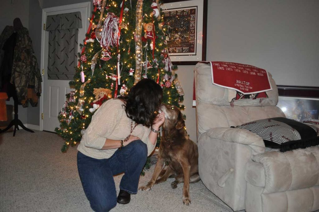 lady kissing dog in front of tree