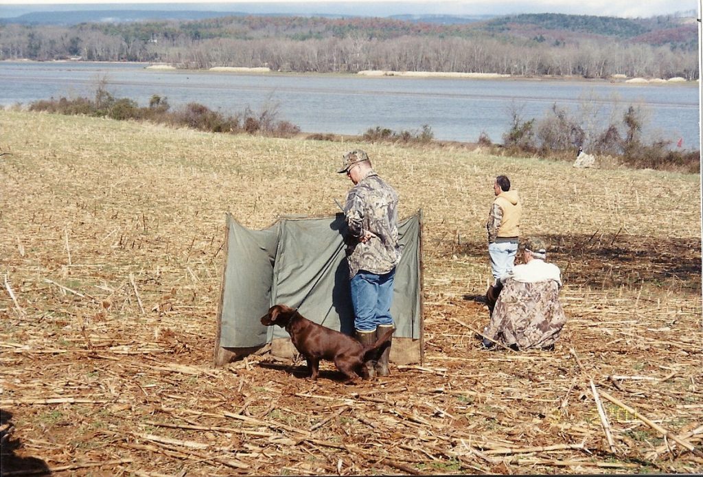 3 men and a dog in hunting blind
