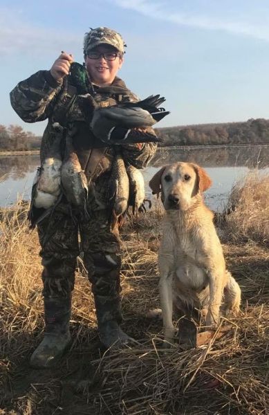person posing with dead duck and dog