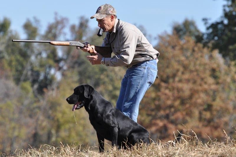 man with duck call and gun and dog